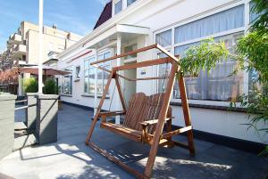 a wooden chair sitting in front of a building at Hotel Zand in Zandvoort