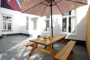 een houten picknicktafel met een parasol op een patio bij Hotel Zand in Zandvoort