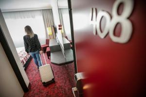 a woman standing in a hotel room with her suitcase at ARCOTEL Nike Linz in Linz