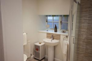 a white bathroom with a sink and a shower at The Old Workshop - Drift in Penzance