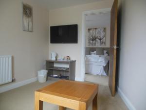 a living room with a table and a tv at Greyhound Inn in Winterborne Kingston