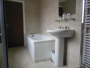 a white bathroom with a sink and a bath tub at Greyhound Inn in Winterborne Kingston