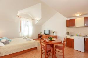 a room with a bed and a table and a kitchen at Apartments Mondo in Mokošica