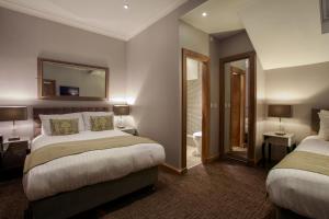 Habitación de hotel con 2 camas y espejo en Angels Hotel, en Uddingston