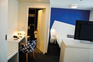 Schlafzimmer mit einem Bett und einem Schreibtisch mit einem TV in der Unterkunft Hôtel ORIGAMI in Straßburg