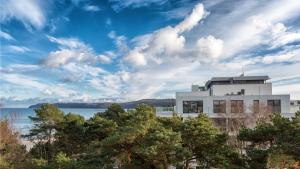 un edificio con árboles frente a un cuerpo de agua en Villa Vogue Gretas Beach Home, en Binz