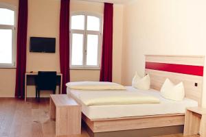 a bedroom with two beds and a desk and window at Hotel-Gasthof Flötzinger Bräu in Rosenheim