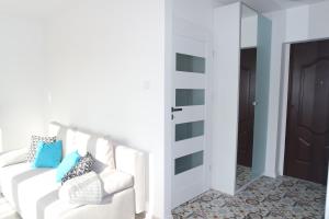 a white living room with a white couch and a mirror at Przy Piastowskiej in Gdańsk