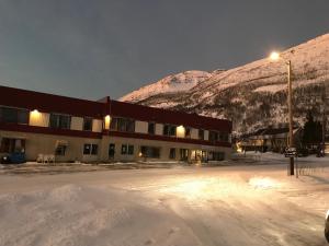 a building in the snow with mountains in the background at Lyngenfjord,Odins Hus in Olderdalen