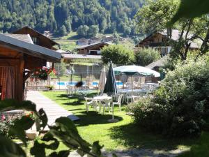 eine Terrasse mit Tischen und Sonnenschirmen im Gras in der Unterkunft Fleur des Neiges in Morzine