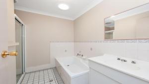 a white bathroom with a sink and a mirror at Peaceful, Quiet and so close to the beach! in Fingal Bay