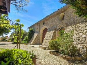 a stone building with a large doorway and a stone wall at La Bastide De Sauvetas in Bonlieu-sur-Roubion