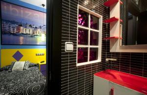 baño con paredes de azulejos negros y ventana en JC Rooms Santa Ana, en Madrid