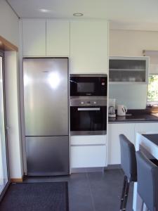 eine Küche mit einem Kühlschrank aus Edelstahl und einer Mikrowelle in der Unterkunft Villa Piscine Portugal in Coucieiro