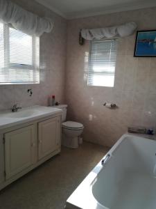 a bathroom with a tub and a sink and a toilet at Avondsrus Guesthouse in Bettyʼs Bay