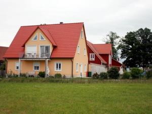 a house with a red roof and a green field at Ferienwohnungen Schlossblick in Muhr amSee