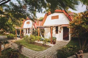 une maison blanche avec un toit orange dans l'établissement Encantada Ocean Cottages, à Esterillos Este