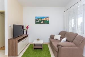 een woonkamer met een bank en een flatscreen-tv bij Apartmani LuNa in Hvar