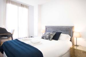 a bedroom with a white bed with a blue blanket at Apartment Alcala 146 in Madrid