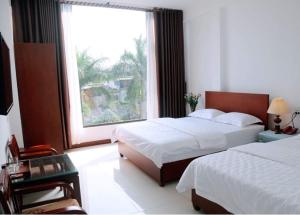 a bedroom with two beds and a large window at Sunflower Hotel in Ninh Binh