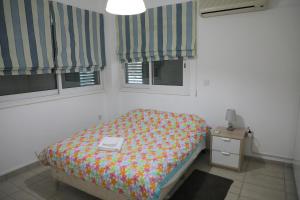 um pequeno quarto com uma cama e 2 janelas em Bianco E U Apartment em Nicósia