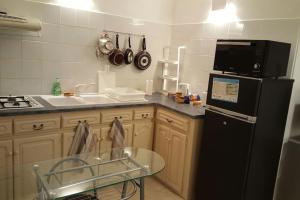 a kitchen with a black refrigerator and a glass table at Appartement Centre Sainte-Clotilde in Sainte-Clotilde