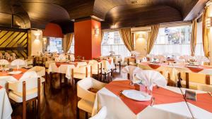 a restaurant with white tables and chairs and windows at San Silvestre Hotel in Passo Fundo