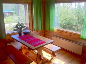 a wooden room with a table and two windows at Tuomarniemi Cottages in Kokonvaara