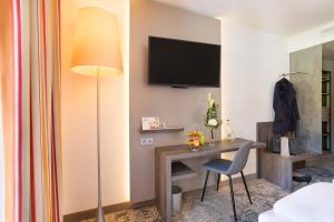 a hotel room with a desk and a television on the wall at Hotel Krämerbrücke Erfurt in Erfurt