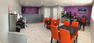 un restaurante con sillas naranjas, mesa y paredes moradas en Super 8 by Wyndham Sonora, en Sonora