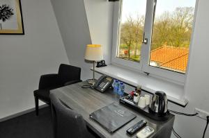 Zimmer mit einem Tisch mit einer Lampe und einem Fenster in der Unterkunft Hotel Parkview in Amsterdam