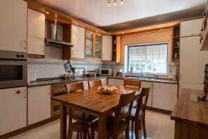 a kitchen with a wooden table with chairs and a sink at Casa das Conchas in Ericeira
