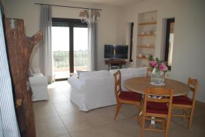 a living room with a table and a white couch at Olive Tree Cottage in Nea Peramos