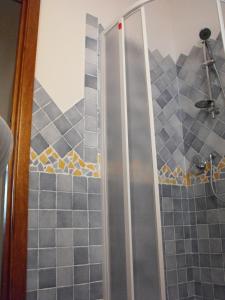 a shower in a bathroom with gray tiles at Case Vacanze - Le Bacche di Maiorca in Budoni
