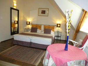 ein Schlafzimmer mit einem Bett und einem Tisch mit einer Vase darauf in der Unterkunft Albergo Giardino in Balatongyörök