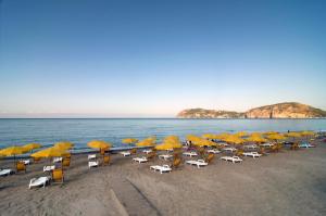 um monte de cadeiras e guarda-sóis numa praia em Villaggio Camping Odissea em Marina di Camerota