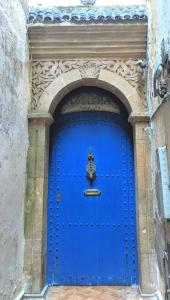 Eine blaue Tür in einem Gebäude mit einem Schild drauf. in der Unterkunft Dar Loulema in Essaouira