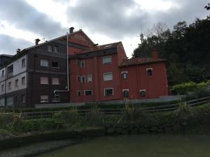 un grand bâtiment rouge à côté d'une rivière dans l'établissement Hotel Derli Sella, à Ribadesella