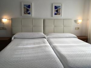two beds in a hotel room with white sheets at Hotel Derli Sella in Ribadesella