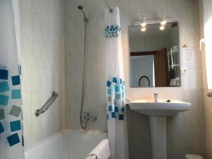 a bathroom with a tub shower and a sink at Hotel Derli Sella in Ribadesella