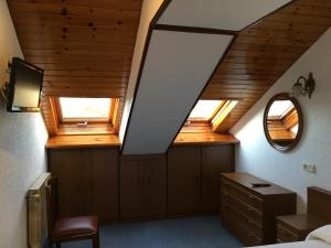 a attic room with a bed and two windows at Hotel Derli Sella in Ribadesella