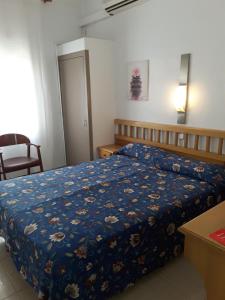 1 dormitorio con 1 cama con edredón azul en Hostal Margarita, en Pineda de Mar