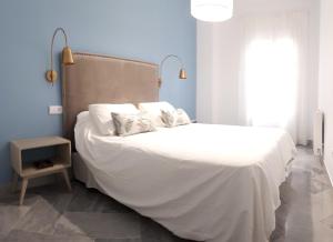 a bedroom with a large bed with white sheets at REGINA apartment in Seville