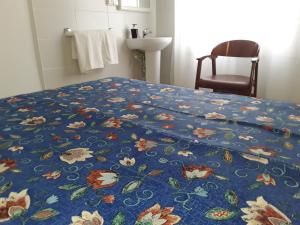 a bed with a blue comforter with flowers on it at Hostal Margarita in Pineda de Mar