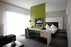 a bedroom with a bed and a desk with a tv at SportHotel Kaiserau in Kamen