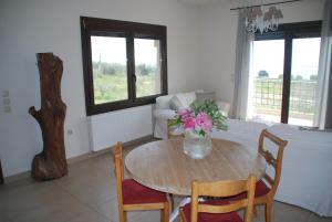 a dining room table with a vase of flowers on it at Olive Tree Cottage in Nea Peramos