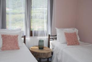 two beds in a room with a window and a table at Olive Tree Cottage in Nea Peramos