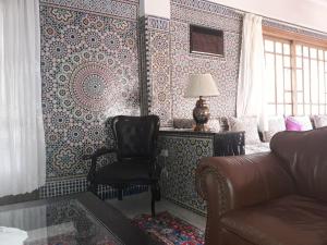 - un salon avec une chaise et des murs à motifs dans l'établissement Villa Tazi, à Meknès