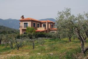 a house in the middle of a field with trees at Olive Tree Cottage in Nea Peramos