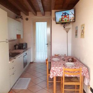 a kitchen with a table with chairs and a television at Appartamenti Esmera in Desenzano del Garda